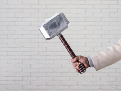 a businessman's hand holding Thor’s Hammer